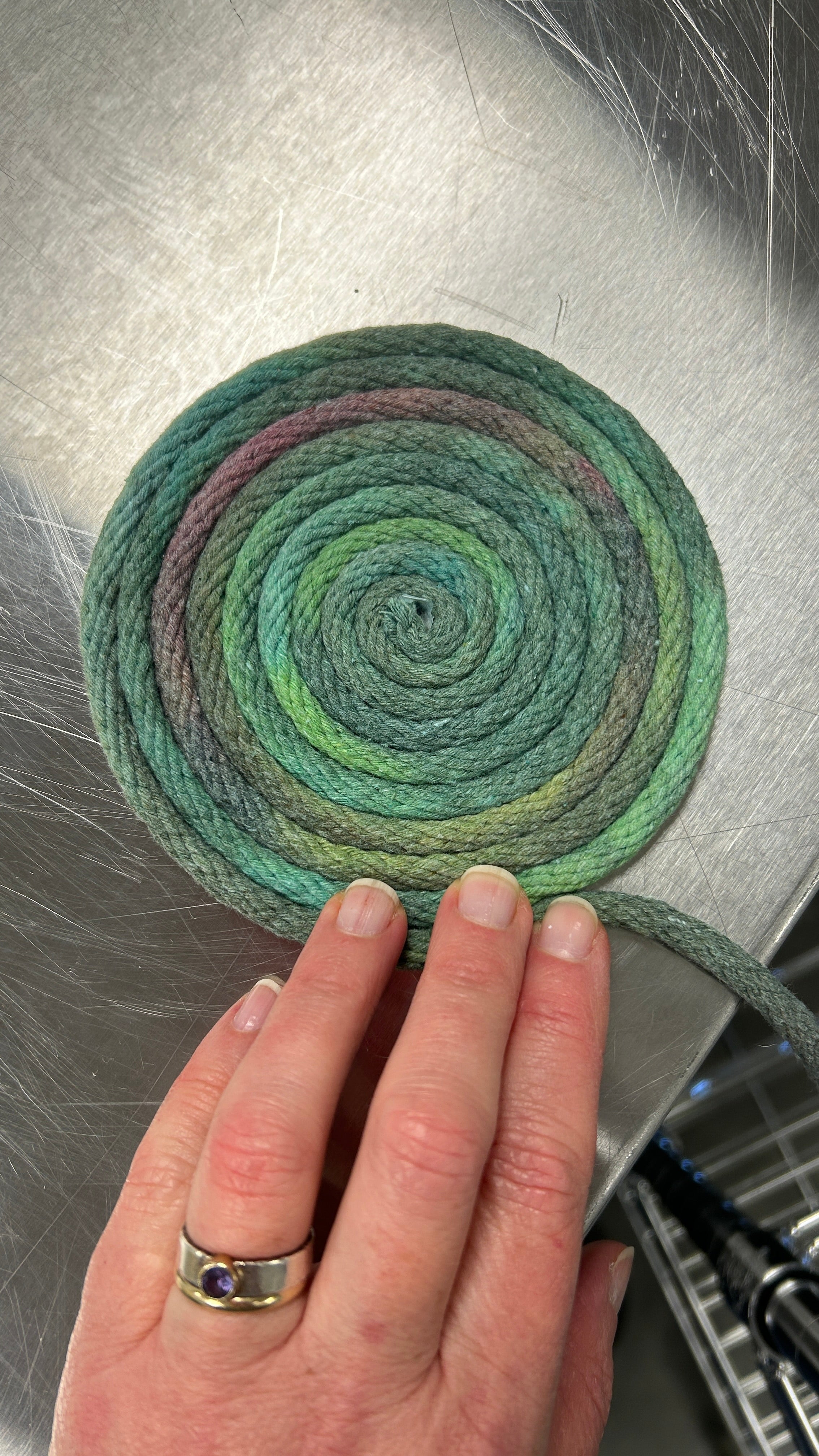 Photo of a hand holding a hand dyed coil of cotton rope